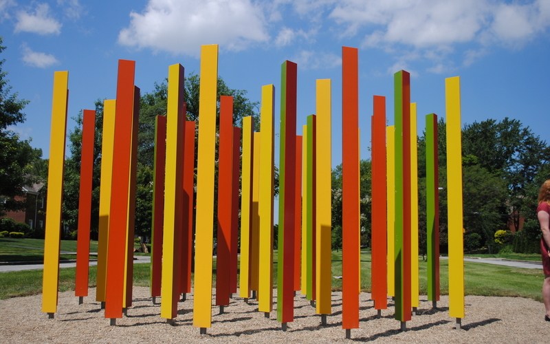 Colorful triangular stainless steel posts are painted a different color on each face, providing a changing view depending on the viewer's perspective.
