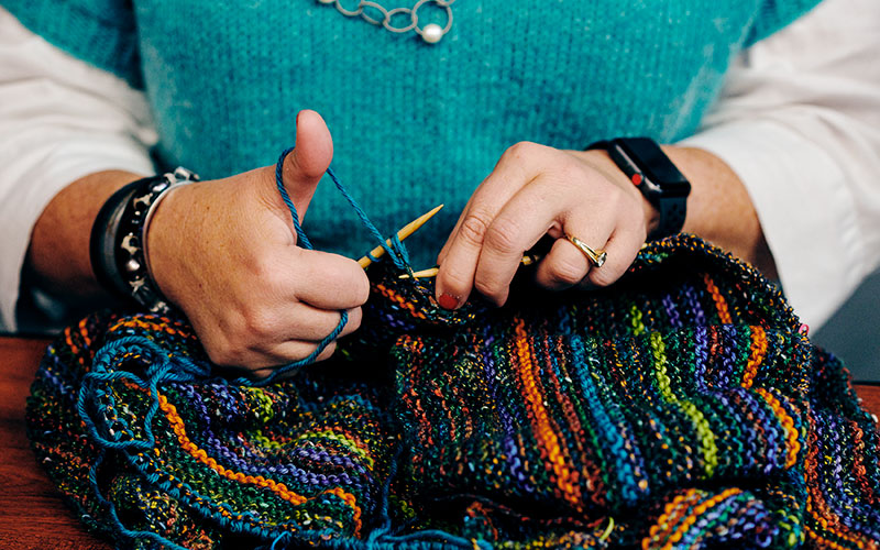 Close up of Pam Berkson, owner of Around the Table Yarns, working on a project