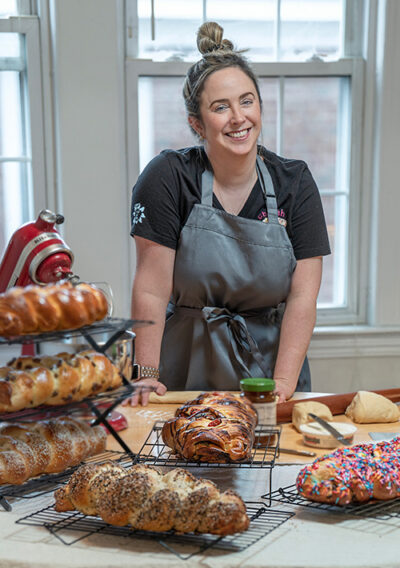 Mghann Hennnen in her kitchen with loaves of cooked challah