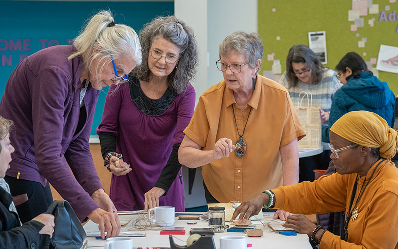 Attendees at Coffee and Community select stamps to use on their accordion pocket file craft.