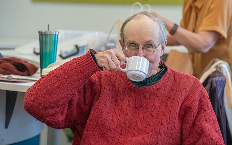 Leslie Ostrander laughs with other attendees. Below: Geoffrey Hare enjoys coffee and conversation.