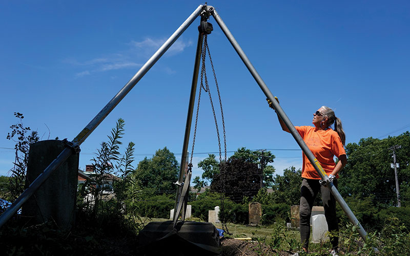 Cemetery restoration expert TaMan Conde restoring a headstone to its upright position
