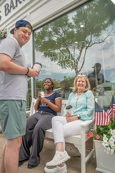 Caroline Weingart, owner of Lizzie’s Bakery (right) taking a break with her son Ethan and Kenardia Smith on a bench in front of the bakery
