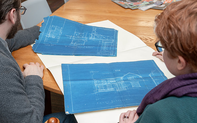 Two individuals looking at blue prints