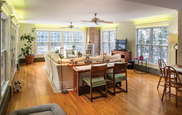 In the existing family room and the new upstairs sitting room outlets were installed under the floorboards to limit the number of wires crisscrossing a room from baseboard outlets. Each outlet is accessed through a wood panel in the floor. The standing lamp behind the couch is over one of those outlets.