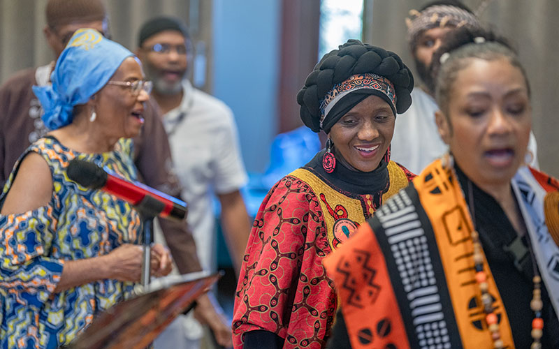 Inez Boon, Berttina Walker, and Linnette E. Lawson process onstage while singing, “Lift Every Voice and Sing.”