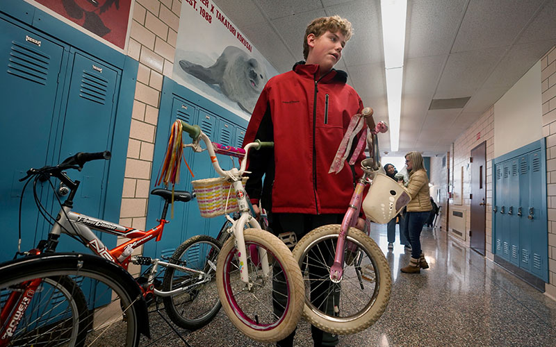 Student carrying a child's bicycle