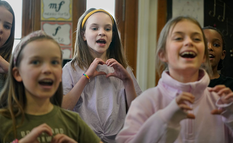 Three female students making heart symbol with their hands