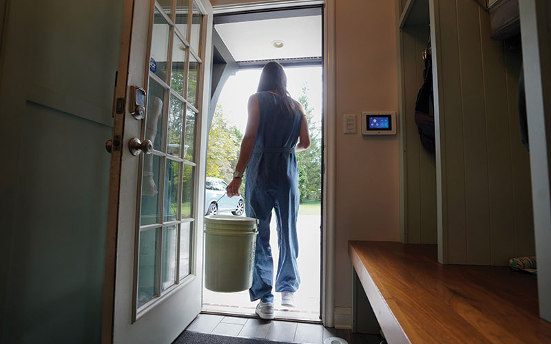 Resident walking out front door with Rust Belt Riders compost pail