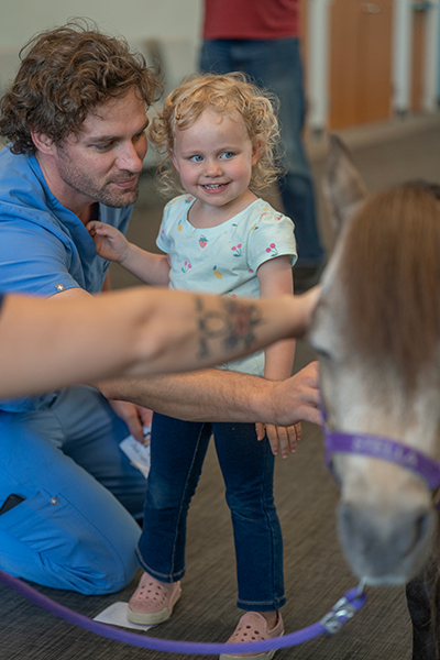 Young child and father petting miniature horse