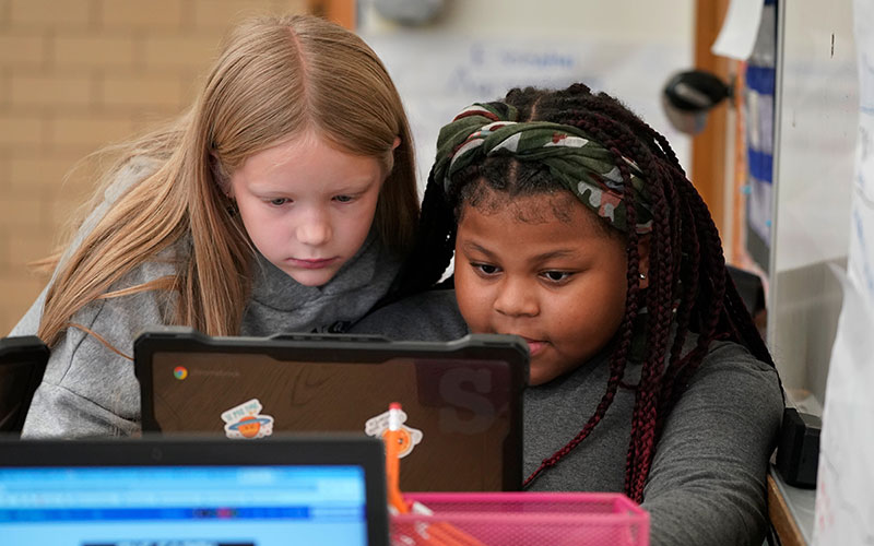 Two school girls working together at a computer