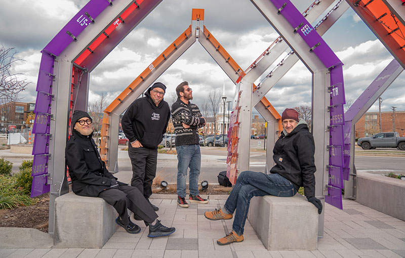 Artists and fabricators of Hear, Here sitting ond standing under the structure